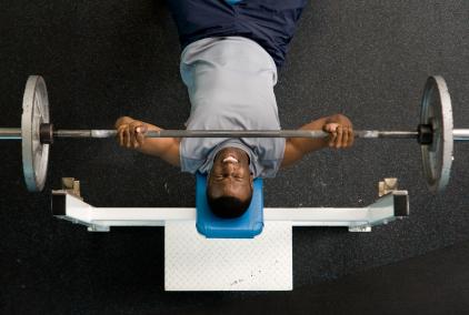 man performing bench press with free weights