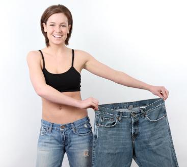 woman who has lost weight holding up a pair of large jeans